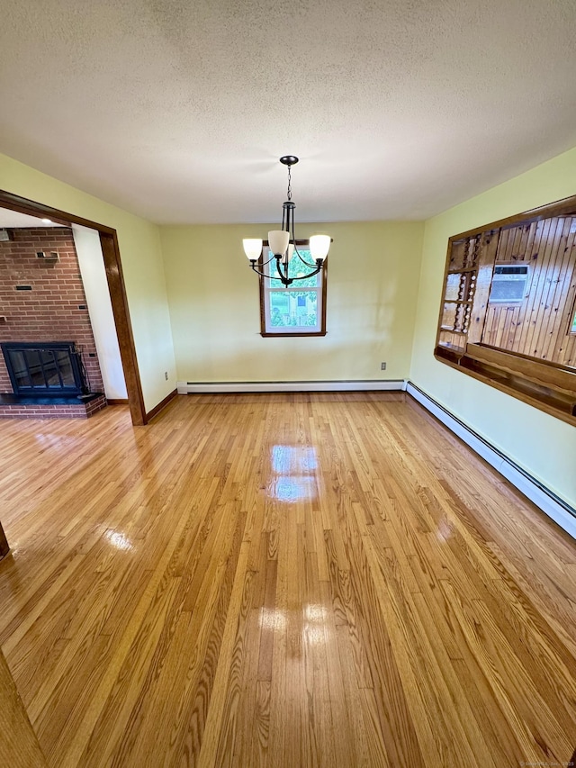 588 Poquonock Ave, Windsor, CT 06095 - unfurnished dining area featuring light wood finished floors, a chandelier, a textured ceiling, baseboards, and a brick fireplace