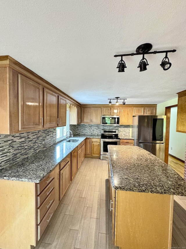 588 Poquonock Ave, Windsor, CT 06095 - kitchen with appliances with stainless steel finishes, a sink, light wood-type flooring, dark stone countertops, and a kitchen island