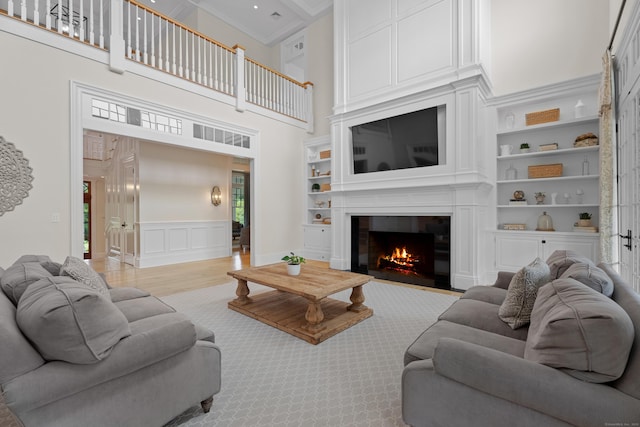 294 Maple Rd, Easton, CT 06612 - living room with a fireplace, crown molding, a towering ceiling, built in shelves, and a decorative wall
