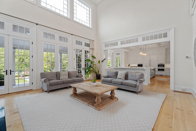 294 Maple Rd, Easton, CT 06612 - living area featuring french doors, a high ceiling, light wood-style flooring, healthy amount of natural light, and a chandelier