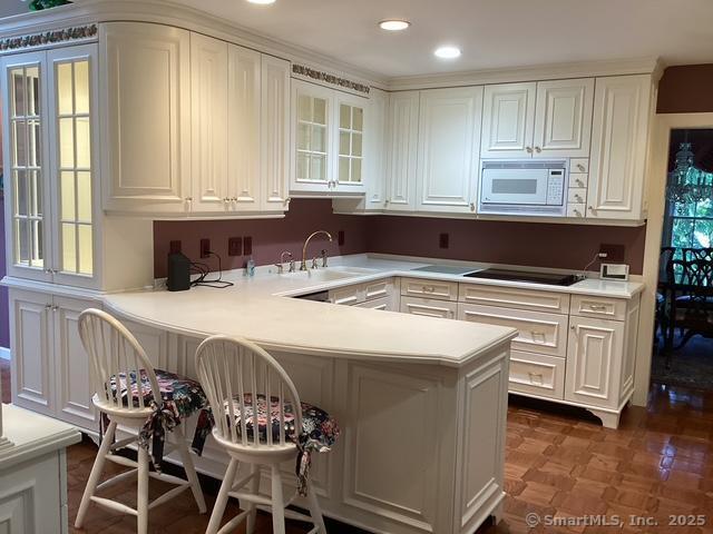 2 Tunxis Pl, Cheshire, CT 06410 - kitchen featuring white microwave, a sink, white cabinetry, a peninsula, and a breakfast bar area