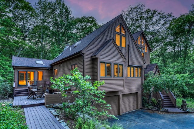 522 Peddlers Rd, Guilford, CT 06437 - back of house at dusk featuring a garage, roof with shingles, a wooden deck, stairway, and driveway