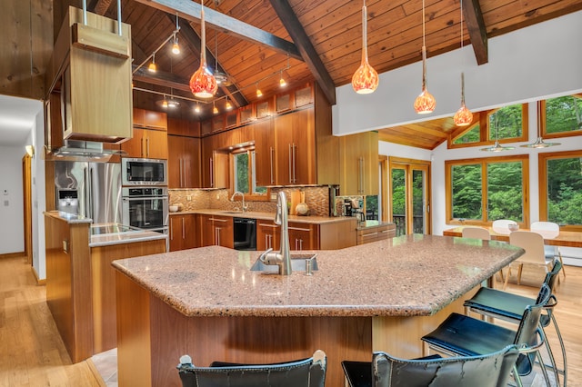 522 Peddlers Rd, Guilford, CT 06437 - kitchen featuring stainless steel appliances, light wood finished floors, a spacious island, brown cabinetry, and a wooden ceiling with exposed beams