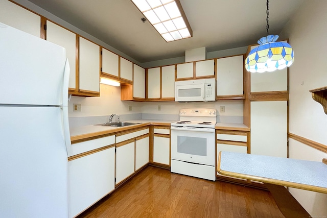 111 Dekoven Dr Apt 506, Middletown, CT 06457 - kitchen with white appliances, a sink, wood finished floors, light countertops, and pendant lighting