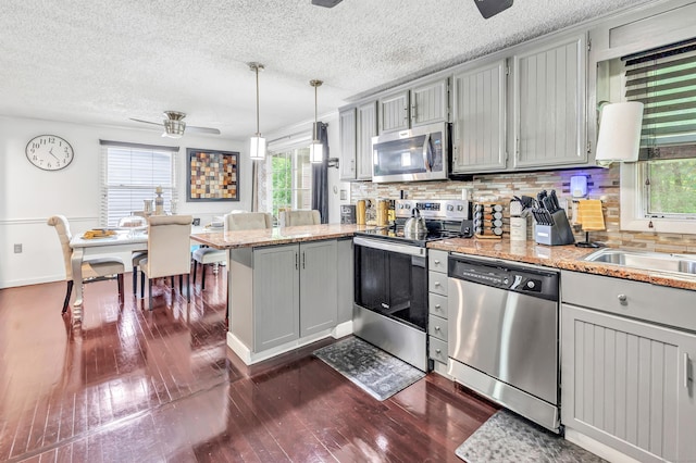 66 Coleman St, West Haven, CT 06516 - kitchen featuring stainless steel appliances, a peninsula, dark wood finished floors, a ceiling fan, and backsplash