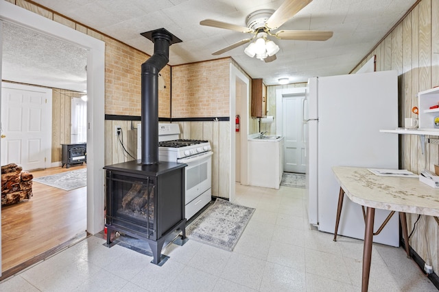 48 Burlington Ave, Bristol, CT 06010 - kitchen featuring a wood stove, white appliances, washer / dryer, light flooring, and brick wall