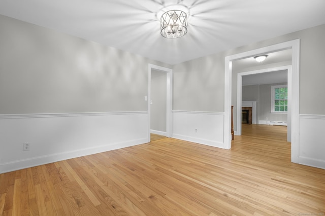 5 Brainerd Dr, Portland, CT 06480 - unfurnished dining area with baseboard heating, light wood finished floors, a brick fireplace, and a wainscoted wall