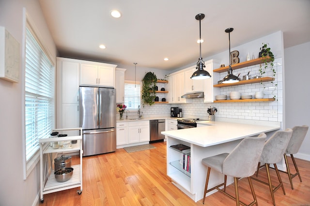35 Ringgold St Unit 401, West Hartford, CT 06119 - kitchen featuring open shelves, stainless steel appliances, under cabinet range hood, a sink, and a peninsula