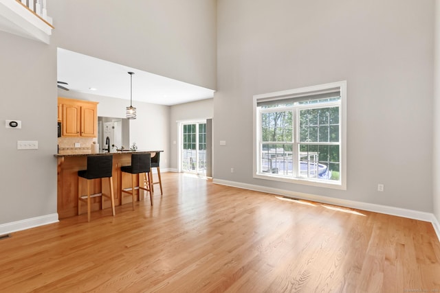 584 Meriden Ave Unit 1, Southington, CT 06489 - kitchen with a breakfast bar, light wood finished floors, baseboards, tasteful backsplash, and a towering ceiling