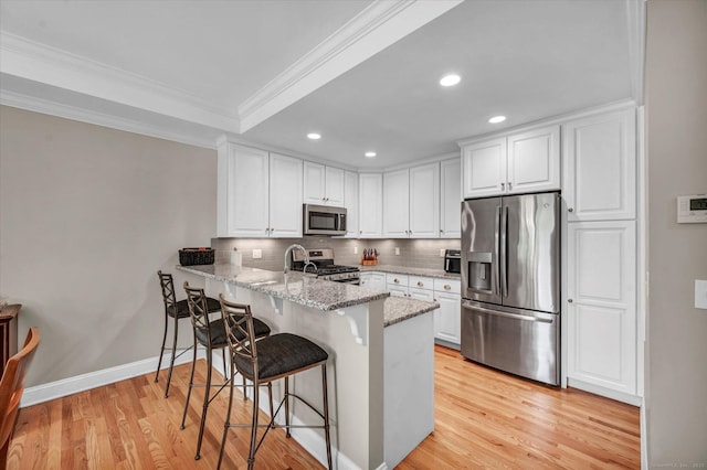 6 Mill Pond Ln Unit A, Simsbury, CT 06070 - kitchen featuring appliances with stainless steel finishes, ornamental molding, a peninsula, a breakfast bar, and decorative backsplash
