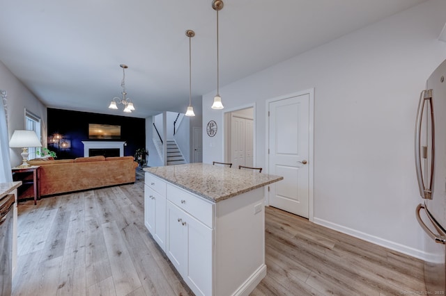 2 Linden Ct, Southington, CT 06489 - kitchen featuring freestanding refrigerator, light wood finished floors, light stone counters, white cabinetry, and decorative light fixtures