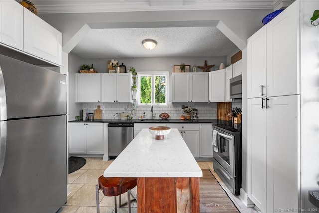 76 Geer Ave, Norwich, CT 06360 - kitchen featuring stainless steel appliances, backsplash, ornamental molding, white cabinets, and a textured ceiling