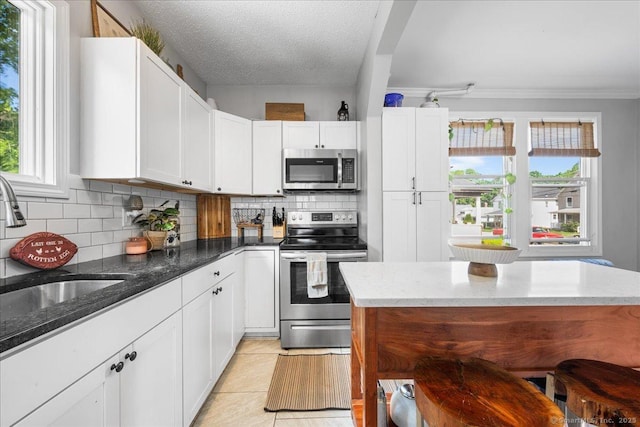 76 Geer Ave, Norwich, CT 06360 - kitchen featuring appliances with stainless steel finishes, decorative backsplash, plenty of natural light, dark stone countertops, and ornamental molding