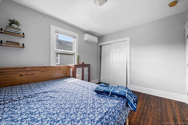 76 Geer Ave, Norwich, CT 06360 - bedroom with a wall unit AC, hardwood / wood-style flooring, baseboards, a closet, and a textured ceiling