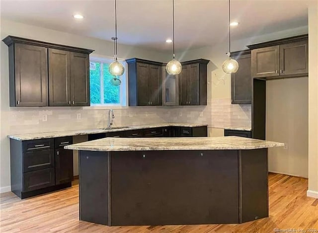 LOT6 Ratlum Mountain Rd, Barkhamsted, CT 06063 - kitchen with backsplash, a sink, light stone countertops, light wood finished floors, and a center island