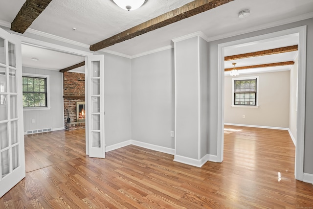 1975 Huntington Rd, Stratford, CT 06614 - unfurnished room featuring a smoke detector, plenty of natural light, beam ceiling, light wood-style flooring, and a fireplace