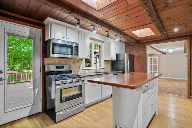 1975 Huntington Rd, Stratford, CT 06614 - kitchen with stainless steel appliances, a wood ceiling with exposed beams, a skylight, rail lighting, and white cabinets