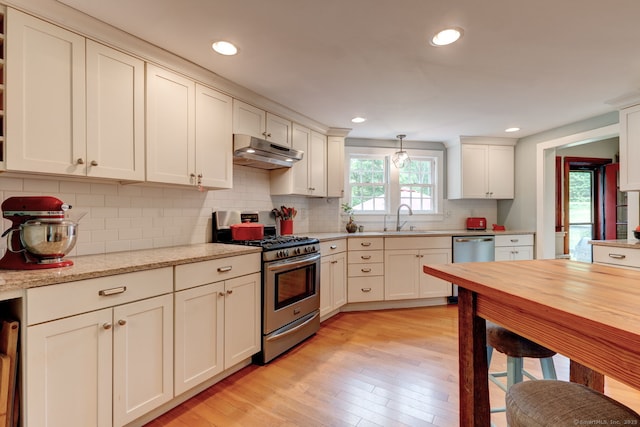 96 Middle Haddam Rd, East Hampton, CT 06456 - kitchen with appliances with stainless steel finishes, under cabinet range hood, a sink, light wood finished floors, and tasteful backsplash