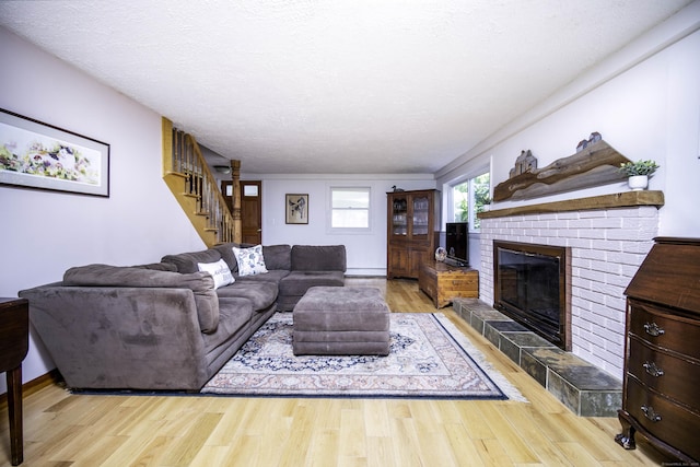 156 Ballamahack Rd, Windham, CT 06280 - living room featuring stairs, a brick fireplace, wood finished floors, a baseboard radiator, and a textured ceiling