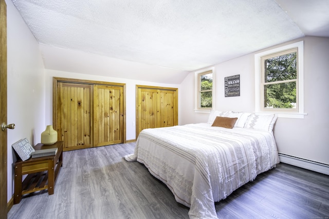 156 Ballamahack Rd, Windham, CT 06280 - bedroom featuring lofted ceiling, wood finished floors, a textured ceiling, a baseboard heating unit, and two closets