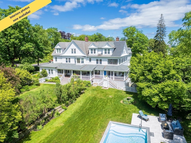 304 Main St, Ridgefield, CT 06877 - rear view of property with a chimney, covered porch, a lawn, and view of wooded area