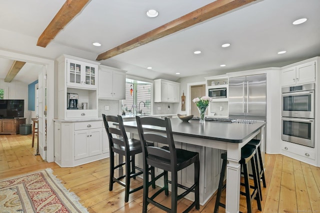 11 Ledgewood Rd, Redding, CT 06896 - kitchen featuring built in appliances, beam ceiling, a breakfast bar area, tasteful backsplash, and light wood-type flooring