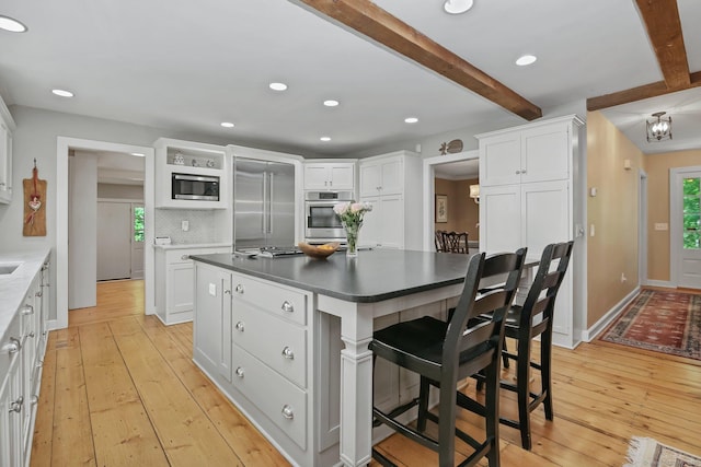 11 Ledgewood Rd, Redding, CT 06896 - kitchen featuring built in appliances, beamed ceiling, plenty of natural light, white cabinets, and light wood-style flooring