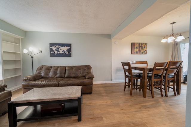 183 Thompson St Unit B, East Haven, CT 06513 - living room featuring light wood-style floors, baseboards, a textured ceiling, a chandelier, and built in shelves