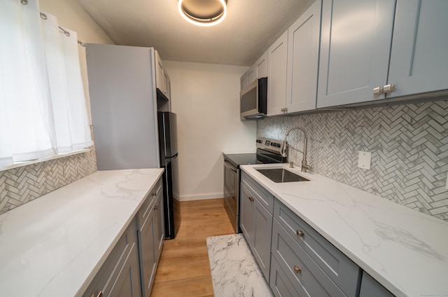 183 Thompson St Unit B, East Haven, CT 06513 - kitchen with appliances with stainless steel finishes, a sink, backsplash, light wood-style floors, and gray cabinetry