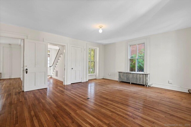 8 Academy St, New Haven, CT 06511 - empty room featuring radiator, hardwood / wood-style floors, stairway, and baseboards