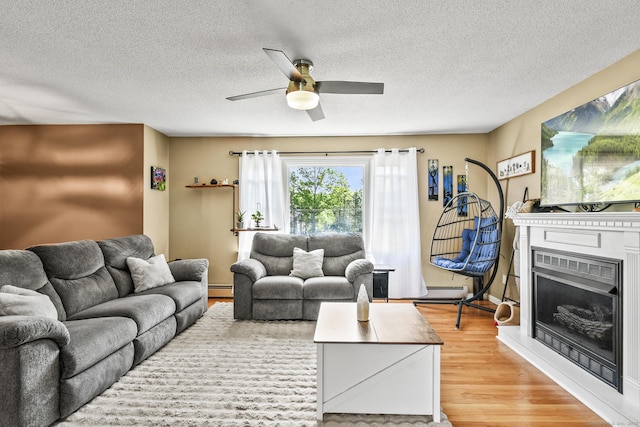 96 Flanders River Rd, Coventry, CT 06238 - living area featuring light wood finished floors, ceiling fan, a textured ceiling, a baseboard radiator, and a fireplace