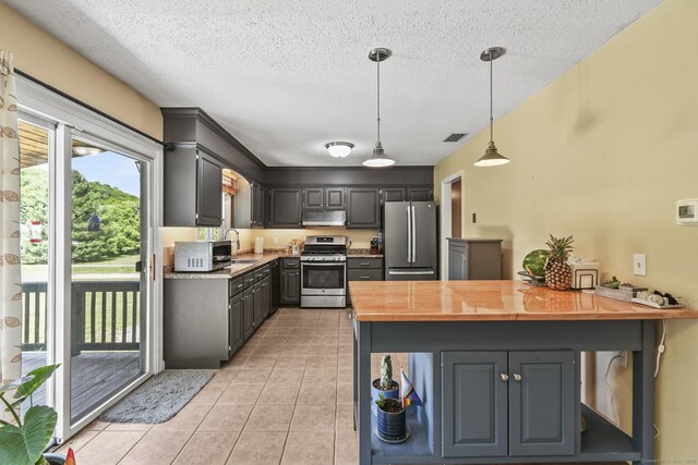 96 Flanders River Rd, Coventry, CT 06238 - kitchen featuring appliances with stainless steel finishes, wood counters, under cabinet range hood, light tile patterned floors, and a textured ceiling