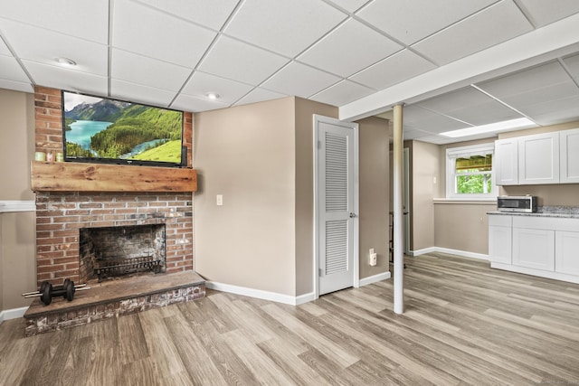 96 Flanders River Rd, Coventry, CT 06238 - unfurnished living room with light wood finished floors, baseboards, a drop ceiling, and a brick fireplace