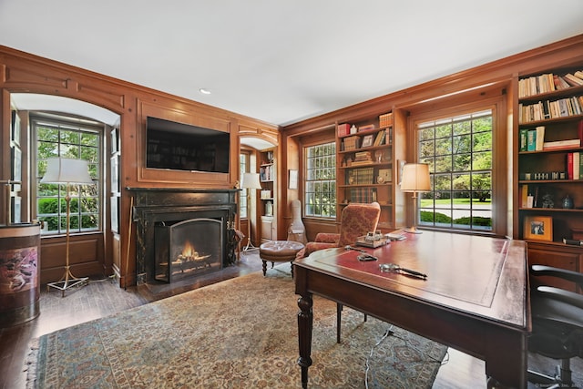 276 Greenley Rd, New Canaan, CT 06840 - office area featuring wood finished floors, built in shelves, a fireplace with flush hearth, and wooden walls