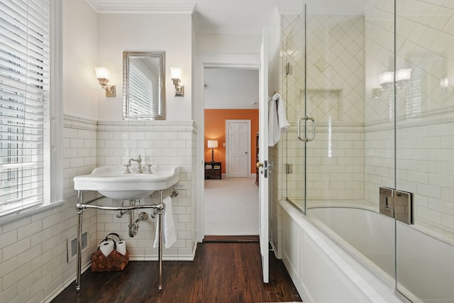 276 Greenley Rd, New Canaan, CT 06840 - bathroom featuring tile walls, wood finished floors, bath / shower combo with glass door, crown molding, and a wainscoted wall