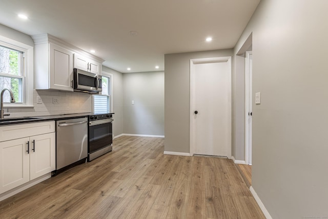 79 Arrowbrook Rd, Windsor, CT 06095 - kitchen featuring appliances with stainless steel finishes, a sink, light wood-style floors, dark countertops, and decorative backsplash