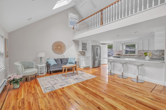 5 Wildmere Ln, Norwalk, CT 06851 - living room with a skylight, high vaulted ceiling, light wood-type flooring, a ceiling fan, and a baseboard radiator