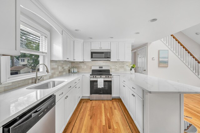 5 Wildmere Ln, Norwalk, CT 06851 - kitchen featuring stainless steel appliances, a sink, a peninsula, decorative backsplash, and white cabinets