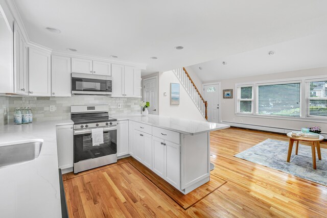 5 Wildmere Ln, Norwalk, CT 06851 - kitchen with stainless steel appliances, light wood finished floors, white cabinetry, a peninsula, and recessed lighting
