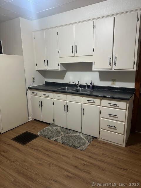 40 Orchard St, Bristol, CT 06010 - kitchen with a sink, freestanding refrigerator, dark countertops, white cabinetry, and dark wood-style flooring