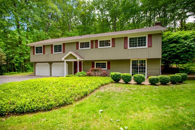 4 Leopard Dr, Newtown, CT 06482 - view of front of home with a chimney, asphalt driveway, an attached garage, a front yard, and view of wooded area