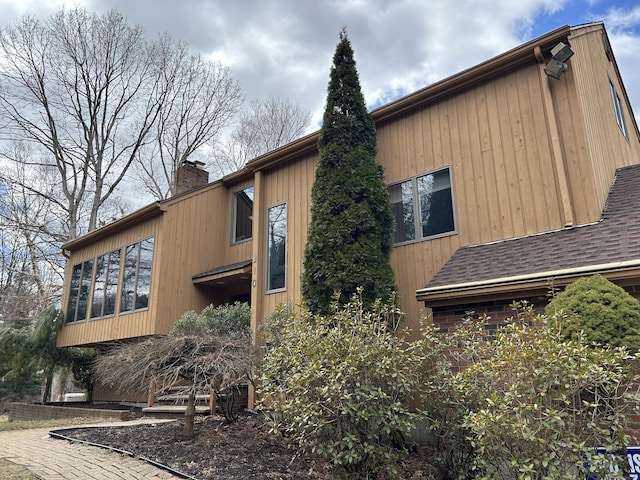 310 Weatherly Trl, Guilford, CT 06437 - view of home's exterior with a chimney, a shingled roof, and a sunroom