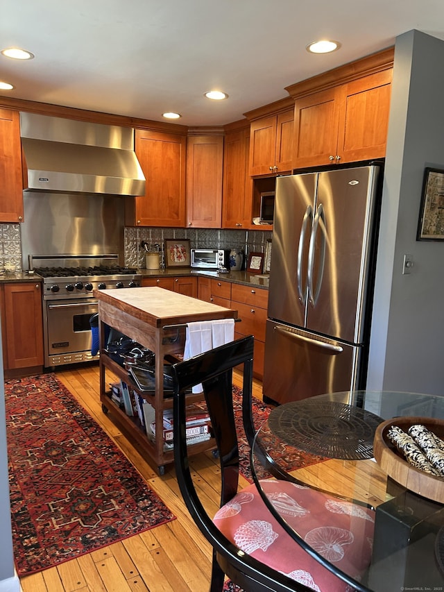 310 Weatherly Trl, Guilford, CT 06437 - kitchen featuring stainless steel appliances, wall chimney range hood, light wood finished floors, brown cabinets, and recessed lighting