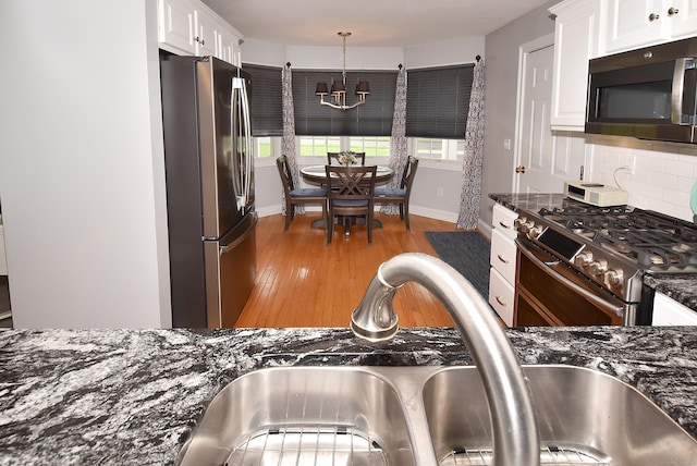 63 Hudson Ln Unit 63, Windsor, CT 06095 - kitchen with appliances with stainless steel finishes, a sink, a chandelier, decorative backsplash, and white cabinets