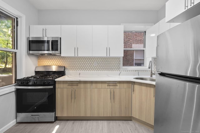 276 Bond St, Bridgeport, CT 06610 - kitchen featuring appliances with stainless steel finishes, a sink, light wood-style flooring, light stone countertops, and tasteful backsplash