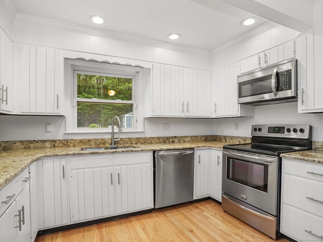 56 Great Neck Rd, Trumbull, CT 06611 - kitchen with appliances with stainless steel finishes, a sink, ornamental molding, white cabinets, and light wood-style floors