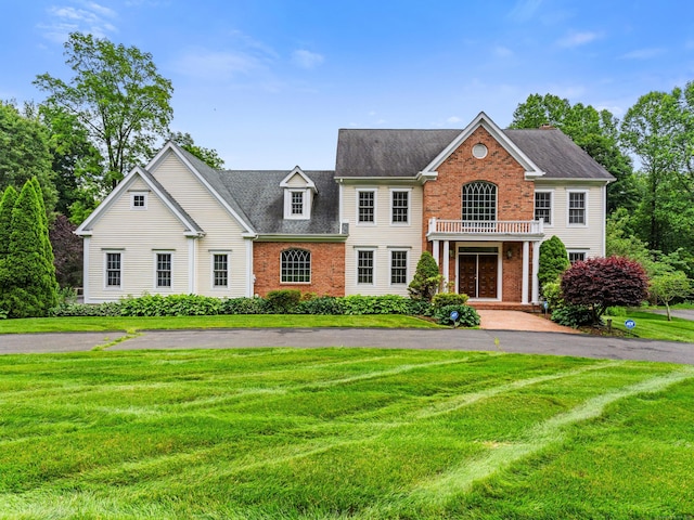 9 Autumn Leaves Rd, Wallingford, CT 06492 - colonial house featuring brick siding, a front yard, roof with shingles, and a balcony