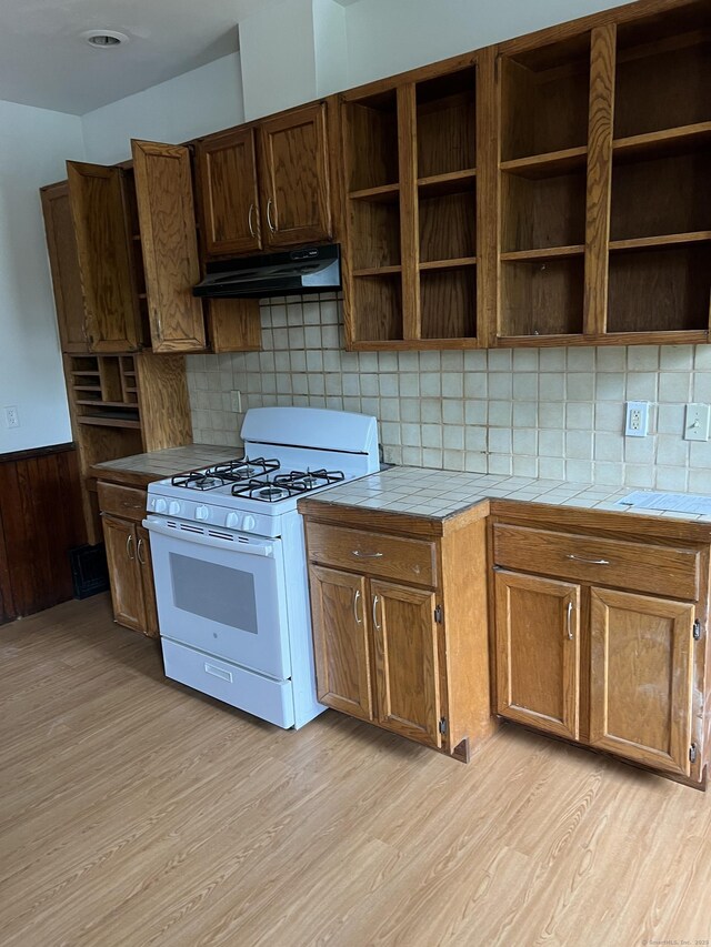 868 Elm St, New Haven, CT 06511 - kitchen featuring white gas stove, under cabinet range hood, tile countertops, light wood-style floors, and open shelves
