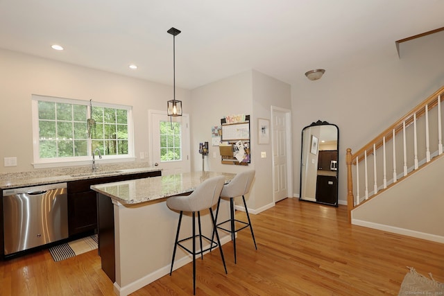 23 Riverview Ct Unit 23, Brookfield, CT 06804 - kitchen featuring stainless steel dishwasher, a sink, light wood finished floors, a kitchen breakfast bar, and light stone counters