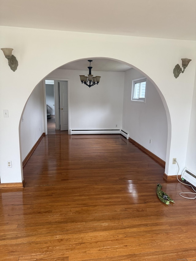 129 Monroe St, East Hartford, CT 06118 - spare room featuring baseboard heating, arched walkways, a chandelier, baseboards, and wood finished floors